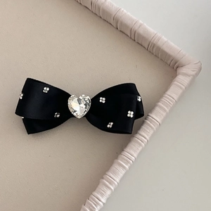 Macro shot of black satin bow hair clip with heart rhinestone and crystal floral details