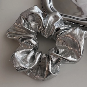 Silver metallic pleated scrunchie with a sleek aesthetic and reflective texture
