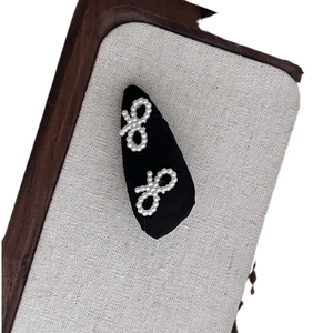 Elegant black fabric bow hair clip with white faux pearl embellishments for women