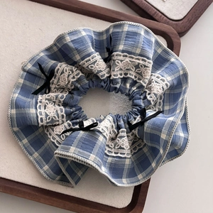 Détail du chouchou à carreaux bleus avec bordure en dentelle blanche et petits nœuds noirs
