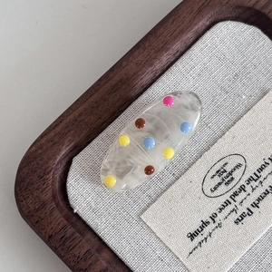 Detail of Korean resin hair clip with colorful 3D dots on a cream base finish