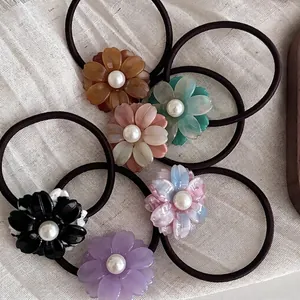 Set of 6 acetate flower hair ties with pearls on textured linen fabric background