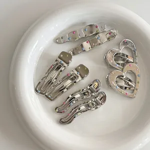 Détail de barrettes en métal argenté avec points colorés pastel sur un plateau en céramique blanc