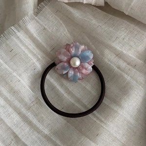 Detail of floral acetate hair tie with blue marble petals and a central white pearl