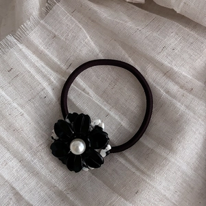 Detailed macro view of black acetate flower hair tie with white pearl and dot patterns