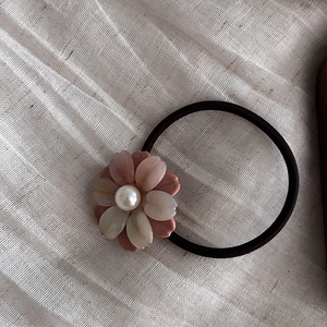 Elegant floral acetate hair tie with pink petals and a white pearl on a soft fabric base