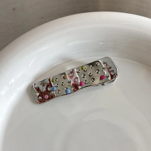 Gros plan d'une barrette à cheveux en métal argenté en forme de pansement décoré