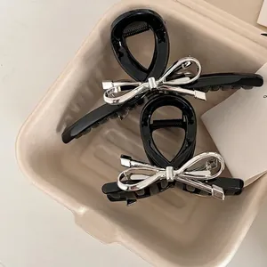 Pince à cheveux papillon noire avec nœud argenté dans un plateau de rangement