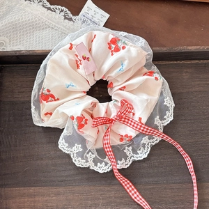 Nahaufnahme von Erdbeer-Lace-Haargummi mit rot karierter Schleife auf Holztablett