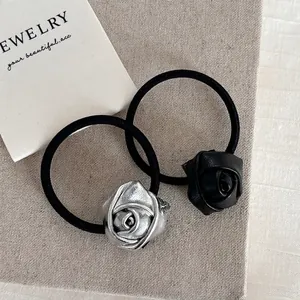 Silver metallic and black matte 3D rose flower hair ties on textured fabric background