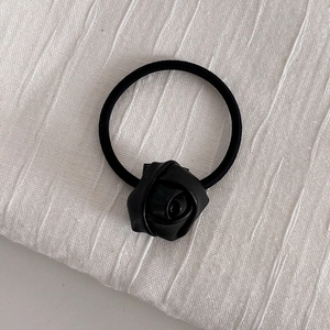 Detailed view of hand-crafted black leather rose flower on an elastic hair tie