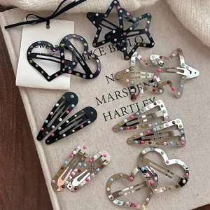 Colorful polka dot metal hair clips in star and heart shapes on a canvas background