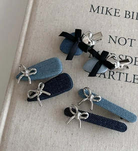 Détail de barrettes en jean avec nœuds et pendentifs cœurs argentés sur un livre