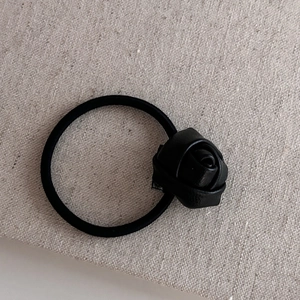 Élastique à cheveux minimaliste avec rose en similicuir noir sur fond en tissu beige
