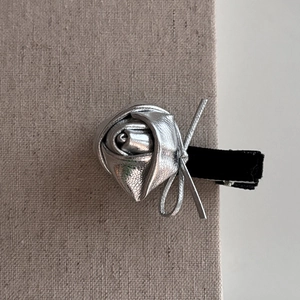 Détail de la pince à cheveux rose en métal argenté avec ruban de velours noir sur lin