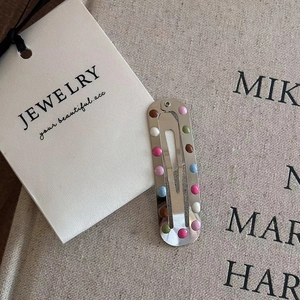 Close-up of a silver star hair clip with colorful candy beads and premium packaging