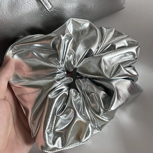 Close-up of a large metallic silver leather scrunchie with rich pleated texture