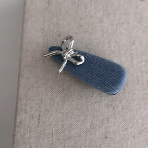 Gros plan d'une pince à cheveux en denim bleu avec nœud métallique argenté