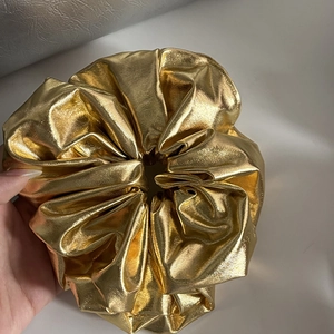 Detailed view of a metallic gold faux leather scrunchie with a reflective mirror finish