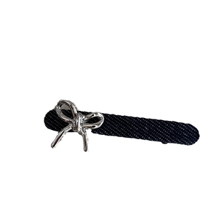 Barrette à cheveux en denim bleu foncé avec un nœud en métal argenté sur fond blanc