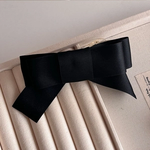 Macro shot of the black satin bow hair clip placed inside a luxury jewelry display box