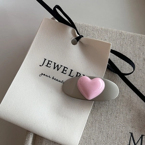 Close-up of sweet pink heart hair clip on gray base with ribbon and card packaging