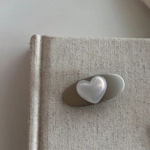 Detailed macro view of the oval matte silver hair clip with a pearlescent heart charm