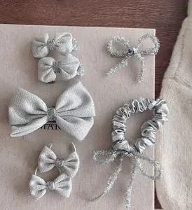 Zilveren haarstrikjes en scrunchie set met glittertextuur op minimalistische achtergrond