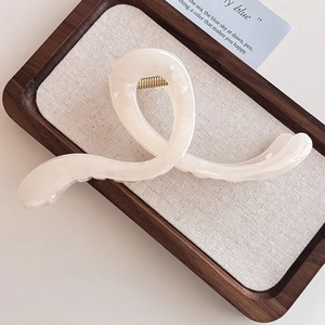 Nahaufnahme der beigen Haarspange mit Perlglanz-Finish auf einem Leinen-Display