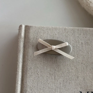 Detailed close-up of a sweet ribbon bow hair clip on a textured linen background