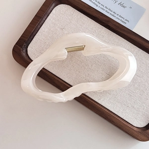 Detailansicht der beigen Haarspange mit Marmortextur auf einem dunklen Holztablett