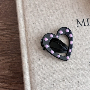 Pince à cheveux cœur noire à pois roses sur un livre vintage pour femmes chic