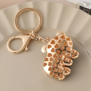 Golden panda bear keychain with heart cutout design on a decorative ripple plate