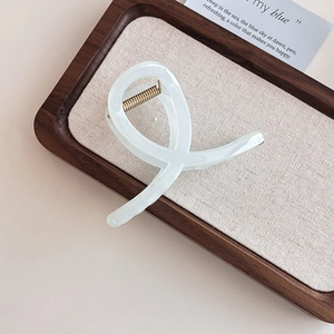 Eleganter beige marmorierter Haarklammer in dunkler Holzschale mit ästhetischer Leinenoptik