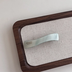 Détail de la pince à cheveux ondulée en acétate vert clair avec logo France Handmade doré