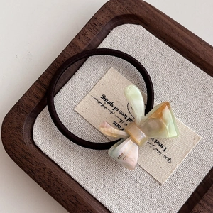 Close-up of handmade amber resin bow hair tie on a high-elastic brown band