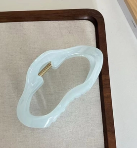 Detailansicht der Haarspange aus Acetat mit hellblau-beigem Marmormuster und Feder