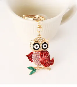 Détail du porte-clés hibou rouge avec strass roses accroché sur une tasse en porcelaine