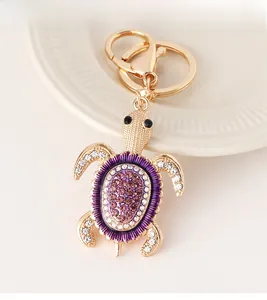 Gros plan d'un porte-clés tortue dorée orné de strass violets et roses et de cristaux brillants