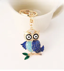 Détail d'un porte-clés hibou doré avec ailes en émail bleu et ornements en strass brillants