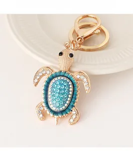 Détail macro d'un porte-clés tortue doré orné de cristaux bleus et d'émail sarcelle