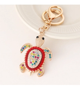 Détail d'un porte-clés tortue dorée orné de strass colorés avec un fermoir mousqueton