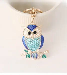 Detailed close-up of a blue owl keychain with crystal rhinestones on a white ceramic bowl
