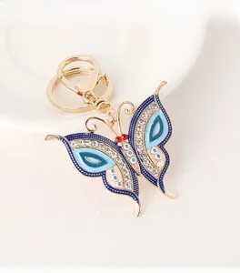 Detail of blue enamel butterfly keychain with colorful rhinestones on a white plate