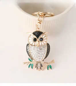 Macro shot of gold owl keychain with white rhinestones and enamel details on branches