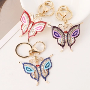 Three colorful butterfly keychains with rhinestones and gold plating on a white surface