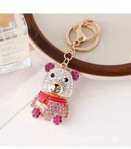Détail d'un porte-clés ours en alliage doré serti de strass et d'une écharpe en émail rouge