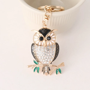 Creative owl keychain with gold metal plating and white rhinestones on a porcelain bowl