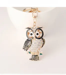 Close-up of owl keychain with sparkling rhinestones and black enamel detail on a cup