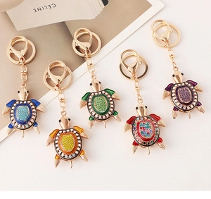 Détail de cinq porte-clés tortue en métal doré sertis de strass multicolores
